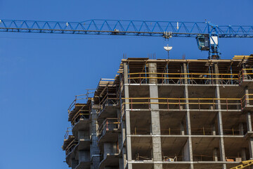 Extensive scaffolding providing platforms for work in progress on a new apartment block,Tall building under construction with scaffolds,Freestanding tower crane on a building site