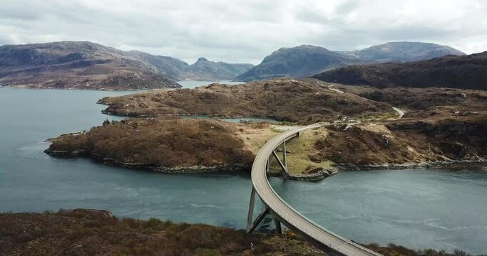 4k aerial footage of famous Kylesku Bridge on NC500 route, Scottish Highlands. No traffic or people, background of loch water and mountains.