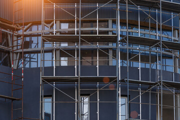 Extensive scaffolding providing platforms for work in progress on a new apartment block,Tall building under construction with scaffolds,Construction Site of New Building © bukhta79