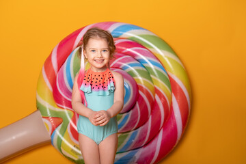 Funny little girl in swimming suit smiling having fun on yellow background.