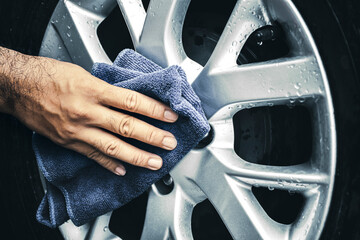 Human hand is wipe the alloy wheel of the car with a microfiber cloth