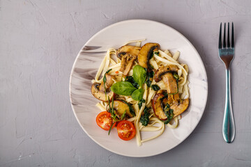 Udon with mushrooms and spinach in a plate on a concrete background.