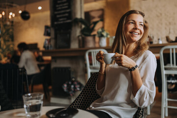 Smiling woman enjoying cup of coffee in the cafe, portrait.