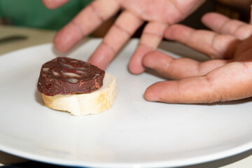 Male hands showing a slice of Argentinean blood sausage slice on a plate