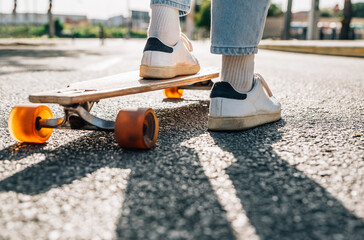 close-up take of the feet of an unrecognizable man on a skateboard on the street asphalt. He is...