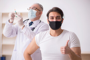 Young male patient visiting old doctor in vaccination concept