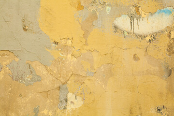 Old dirty yellow stucco plaster wall background. Painted grunge cement concrete wall texture