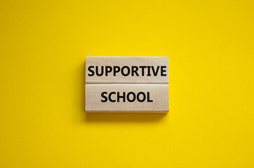 Supportive school symbol. Wooden blocks with words 'Supportive school' on beautiful yellow background. Business and supportive school concept. Copy space.