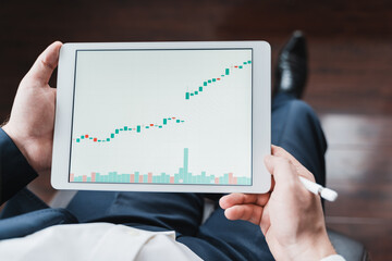 Businessman, investor,trader analyzing,looking at chart of stock prices in tablet. CEO,general manager.Bank investment.Finance company,hedge fund.Japanese candlestick,diagram