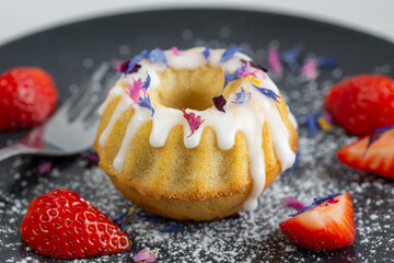 mini bundt cake and strawberries on a black plate close up