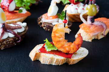 Creative Spanish sandwich that resembles a boat with a sail, consisting of cream cheese, radish, red pepper, and octopus with tentacles