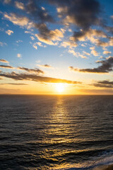 A dramatic sunset over the ocean with colorful skies and color being reflected in the waves below.
