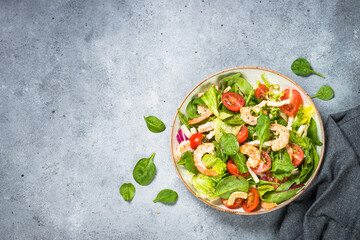 Shrimp salad with green leaves at stone table.