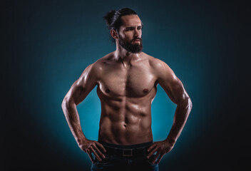 Fototapeta na wymiar Studio portrait of a beautiful masculine bearded shirtless man showing his abdomen muscles