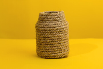 decorative vase made of jute rope on a yellow background