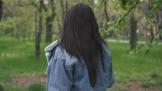 Beautiful longhaired indian in denim jacket woman walking in the park 