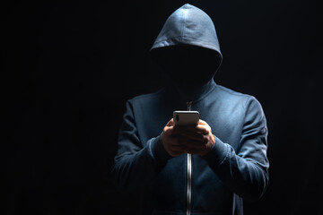 holds the phone on a dark background. hacker concept