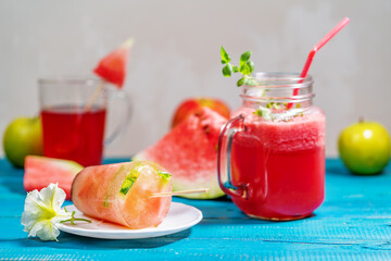 Watermelon smoothie in a glass glass next to fruit ice
