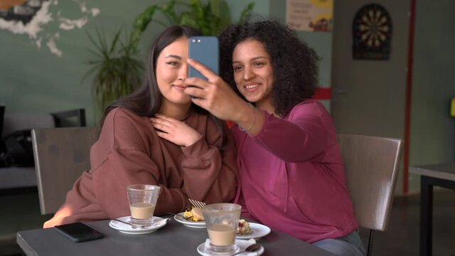 Asian and African American  Smiling Women Make A Photo At the Restaurant