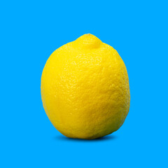 Minimal summer food concept. Yellow lemon citrus fruit isolated and casting shadow on blue vivid background with copy space