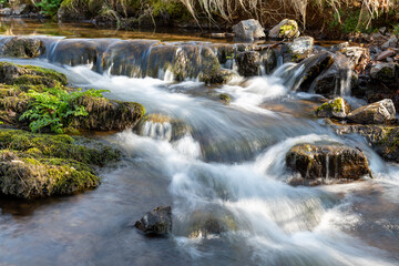 Fototapeta na wymiar Long exposure of the Weir Water river flowing through the valley at Robbers Bridge in Exmoor National Park