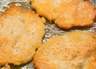 Potato pancakes on ceramic green frying pan closeup. Selective focus.