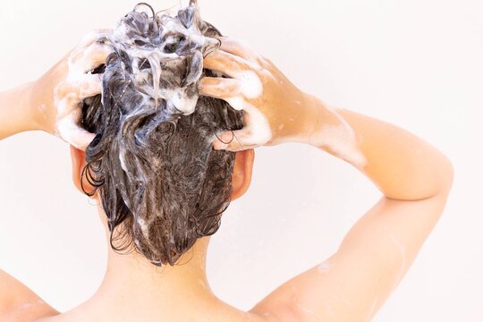 A woman washing and shampooing her hair in the shower. Hygiene and beauty.