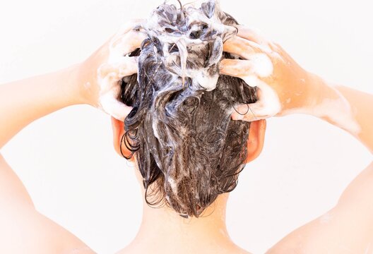 A person taking a shower washing hair and body. Shampoo and water.