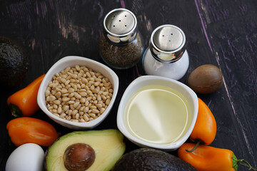 Green fresh organic avocado, pepper, eggs with pine nuts and avocado oil on dark background 
