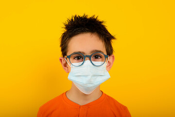 Portrait of a child with face mask for covid-19 coronavirus. yellow background