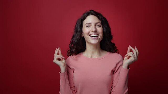 Young happy woman get idea how to a lot of earn money, rub fingers and show scatter cash gesture. Smart female with stratup for big financial profit smiling excitedly over red studio wall background