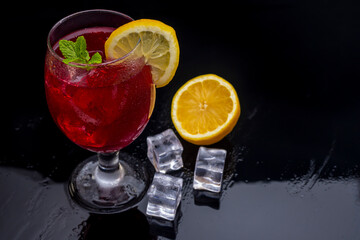 Refreshing cocktail (Red Summer Wine) on black methacrylate background. Concept of fun and social life in bars and pubs. Horizontal photo and selective focus