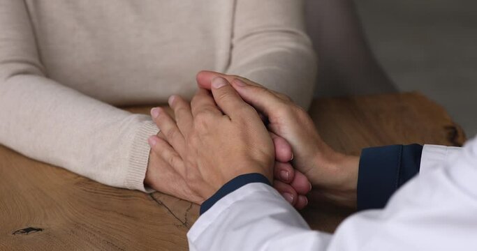 Female therapist in white coat holding hand of senior woman client patient having disease health problem, gives encouragement, provide psychological support. Empathy and comfort concept, close up view