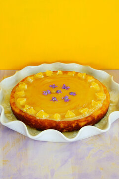 A Round Boiled Meyer Lemon, Almond And Olive Oil Cake With Sliced Lemons And Fresh Violets On Top