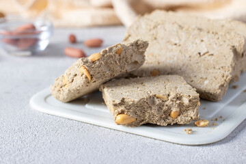 Sweet sunflower halva with peanut on white board on light gray background. Close-up