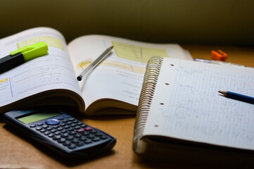 Table with a book, a notebook with math exercises, a calculator and a pen
