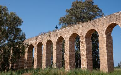 Fototapeta premium The 200 year old Ottoman aqueduct, supplied water from Cabri springs to Acco, western Galilee, Israel. Middle aged female posing at the upper line of the aqueduct.