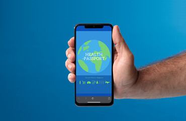 phone in hand with covid passport on screen, with blue background.