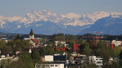 Church of Wetzikon and snow capped mountains.