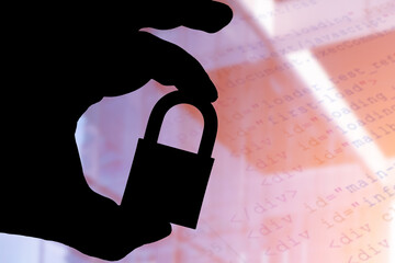 In this photo illustration a man holds a padlock and in the background the html code on the computer screen. Online data protection - breach concept. Internet privacy issues.