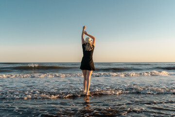 Fototapeta na wymiar Blonde woman on the beach at sunset enjoying her freedom and empowerment.