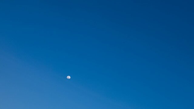 Full Glowing day time Moon timelapse In The Blue Sky Above