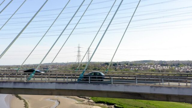 Modern bridge drone shot tracking cars as they drive over Flintshire bridge in Wales. Long fast sliding drone shot.