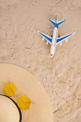 Fototapeta na wymiar Airplane model, straw hat and sunglasses on the sand. Summer vacation concept