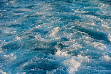 Bubbling blue waves of traces of tourist cruise ships passing on the Bosporus. Water trail foaming behind a passenger ferry boat in Bosphorus, Istanbul, Turkey.