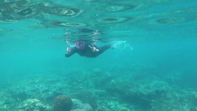 Happy woman snorkeling and playing underwater with fish at Karimun Jawa