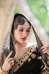 Portrait of beautiful young asian Thai girl. Woman model with traditional India black and gold costume.