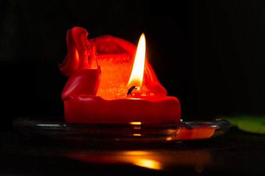 lit candle with red wax over black background