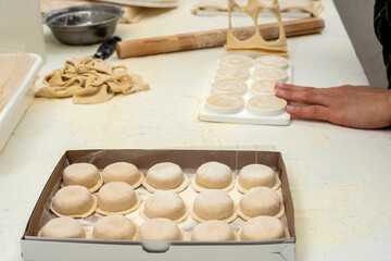 hands arranging fresh homemade sorrentino pastas in boxes for delivery on counter with flour and work items