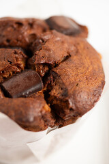 Freshly baked extra large chocolate muffin on a white background.